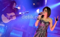 Meski membawakan musik rock, Dewi tampil dengan busana yang sangat feminim, yakni mengenakan dress berwarna silver dan bling-bling
