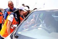 Dengan menggunakan rompi berwarna oranye dan topi putih, terus memperlihatkan senyum manisnya, saat menawarkan penggunaan e-Toll Card kepada pengendara mobil yang melintas.