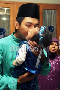 Dengan rasa penuh cinta, Tommy menggendong dan mencium sang buah hati.