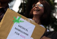 Seorang wanita, dari Lingkar Ganja Nusantara dengan membawa poster ganja, memperlihatkan senyum ramahnya, saat melakukan aksi unjukrasa.