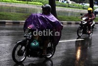 Seorang pengendara sepeda motor menerobos hujan dengan menggunakan jas hujan jenis ponco di Kawasan Sudirman, Jakarta, Senin (7/5/2012).