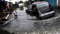 Kendaraan melintasi genangan air di kawasan Kapuk Poglar, Jakarta.