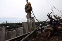 Satu per satu turap beton ditancapkan dengan alat berat.