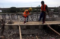 Beberapa pekerja tengah memasang turap yang terbuat dari beton. Pemasangan turap diharapkan dapat menahan tanggul agar tidak longsor.