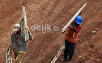 Dua pekerja sedang membawa besi untuk tangga pengerjaan proyek pembangunan jalan layang non tol Kampung Melayu-Tanah Abang.