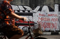 Pengguna jalan melintasi coretan dinding atau mural yang berisikan tentang korupsi di kawasan Simprug, Jakarta.