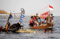 Nelayan melarung sesaji ke tengah laut.