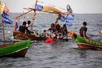 Para nelayan melepas sesaji di tengah laut.