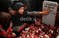 Istri Didik Nur Yusuf tak kuasa menahan kesedihan. Ia terus menangis sambil memegangi nisan suaminya.