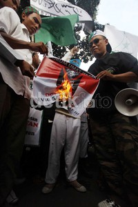 Pendemo membakar poster bergambar Lady Gaga.