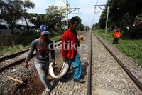 Beberapa pekerja memindahkan batu-batu yang menutupi rel kereta.