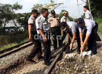 Petugas PT KA mengeruk batu yang menutupi rel di kawasan Palmerah, Jakarta.