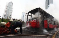 Petugas pemadam kebakaran berusaha memadamkan api yang membakar bus TransJ.