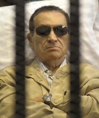 Mubarak yang berkacamata hitam mendengarkan vonis yang dibacakan majelis hakim. Reuters/Stringer.