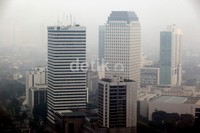 Sebagian gedung pencakar langit di kota Jakarta tampak tertutup kabut.