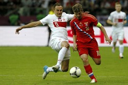 Dariusz Dudka berusaha menghentikan pergerakan Andrey Arshavin. Reuters/Pascal Lauener.