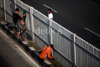 Seorang pejalan kaki menyeberang jalan dengan memanjat pagar pembatas di Jalan Matraman Raya, Jakarta.