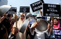 Para pendemo membawa peralatan dapur untuk menunjukan beban ekonomi yang tinggi akibat biaya pendidikan yang mahal.