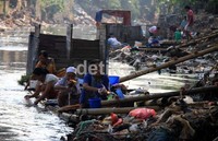 Warga mencuci dengan memanfaatkan air Sungai Ciliwung yang kotor.