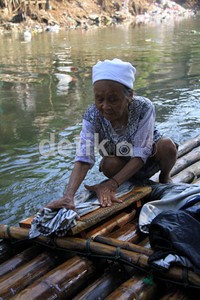 Seorang nenek mencuci memanfaatkan air Sungai Ciliwung yang kotor. Kondisi sanitasi yang buruk membuat daerah seperti Kota Jakarta kehilangan untuk memanfaatan air bersih dari sungai.