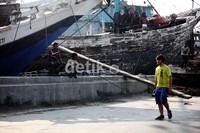 Seorang turis berjalan di depan kapal-kapal yang tengah bersandar di Pelabuhan Sunda Kelapa, Jakarta.