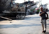 Seorang wisatawan asing berjalan di depan kapal yang sedang melakukan bongkar muat di Pelabuhan Sunda Kelapa, Jakarta.
