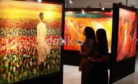 Dua orang pengujung mengamati salah satu lukisan karya Iswanto yang dipamerkan.