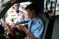 Petugas menertibkan seorang supir mikrolet yang merokok di dalam kendaraan.