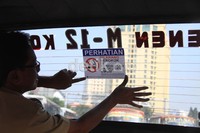 Petugas menempelkan stiker dilarang merokok di dalam angkot.