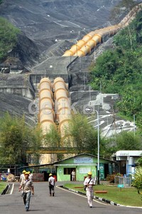 Pekerja melintas di depan pipa pesat sepanjang 1 km yang berguna untuk mengalirkan air dari waduk ke turbin.