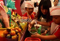 Seorang anak diajari cara melayani pembeli.