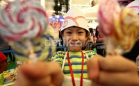Seorang anak menunjukkan beberapa permen yang dijualnya. Hasil penjualan tersebut nantinya akan disumbangkan ke panti asuhan.