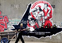 Seorang warga melintas di depan mural di kawasan Daan Mogot, Jakarta, Jumat (6/7/2012).