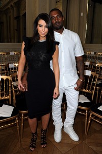 Dibalut dengan baju dan sepatu serba putih dari atas sampai bawah, Kanye tampak serasi dengan Kim yang memakai dress dan heels hitam. Pascal Le Segretain/Getty Images.
