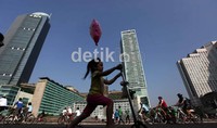 Anak kecil ini juga tampak gembira bisa bermain skuter dan mondar mandir di depan bunderan patung selamat datang.