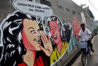 Seorang warga melintas di depan mural Pilkada di Jalan Daan Mogot, Jakarta.