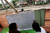 Petugas menuliskan hasil perhitungan suara.
