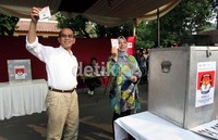 Faisal dan istri menunjukkan surat suara sebelum dimasukkan ke kotak suara.