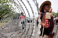 Suwandi mengenakan tutup kepala caping, baju surjan, dan celana pendek serta sandal gunung.  Sedangkan, istrinya memakai kebaya merah.