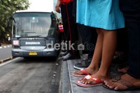 Warga dengan sabar menunggu kedatangan bus yang akan ditumpanginya.