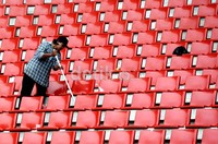Seorang pekerja tengah melakukan perawatan dengan membersihkan bangku di tribun penonton.