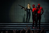 Penyanyi kelahiran 16 Agustus 1958 itu berpose sambil memegang senapan di atas panggung. Ian Gavan/Getty Images.