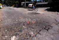 Pengendara sepeda melintas di Jalan Raya Letda Nasir, yang kondisi aspalnya terkelupas.