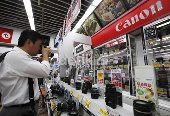 Seorang warga mencoba produk kamera Canon. Krisis zona Euro membuat permintaan menurun dan mendorong penguatan nilai yen.