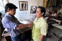 Seorang konsumen tengah mengukur pakaian yang akan dipesan.
