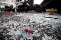 Kaca depan truk pecah dan berserakan di jalan. Stiker bertuliskan Pergi Pagi Pulang Petang yang tertempel di truk juga terlepas.