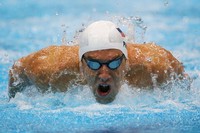 Aksi Phelps saat  melintasi trek 200 meter nomor tunggal di Olimpiade London. Bernama lengkap Michael Fred Phelps II, Phelps lahir di Maryland, AS 30 Juni 1985. Ia memulai debut olimpiade pada Olimpiade Sydney tahun 2000. Waktu itu, usianya masih 15 tahun dan merupakan atlit termuda dalam 68 tahun terakhir. (Foto: Clive Rose/Getty Images)