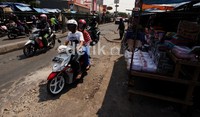 Pengendara melintas di Jalan Ir H. Juanda, Kota Bekasi yang rusak dan berlubang. Di bulan suci Ramadhan, para pedagang kai lima pun semakin menguasai jalan utama.