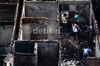 Warga mencari barang-barang yang masih bisa diselamatkan di antara puing-puing kebakaran.