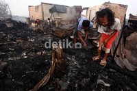 Beberapa warga mencari barang berharga di antara puing-puing kebakaran.
